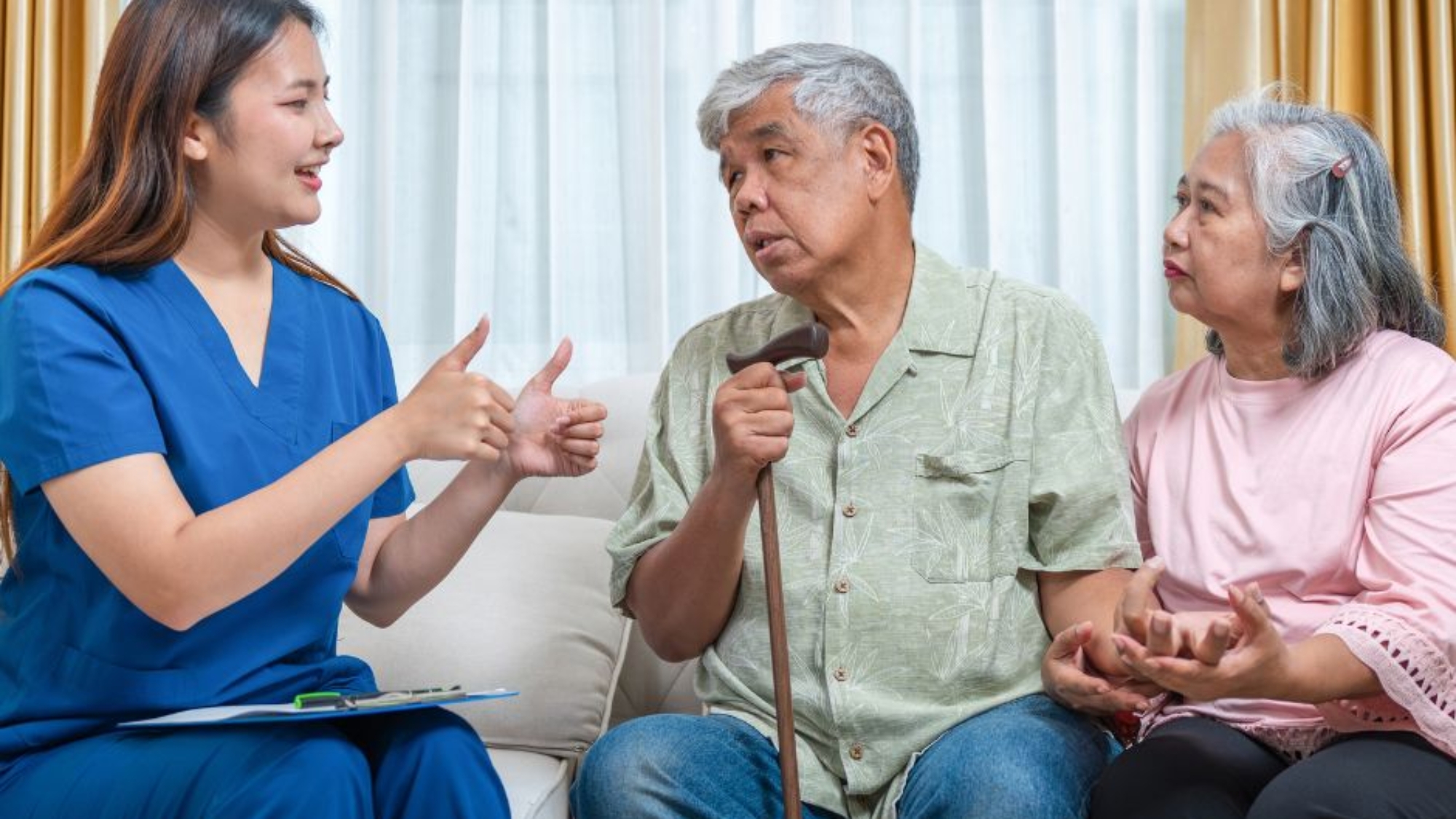 Caregiver speaking with an older couple in their home while discussing in-home care and support options