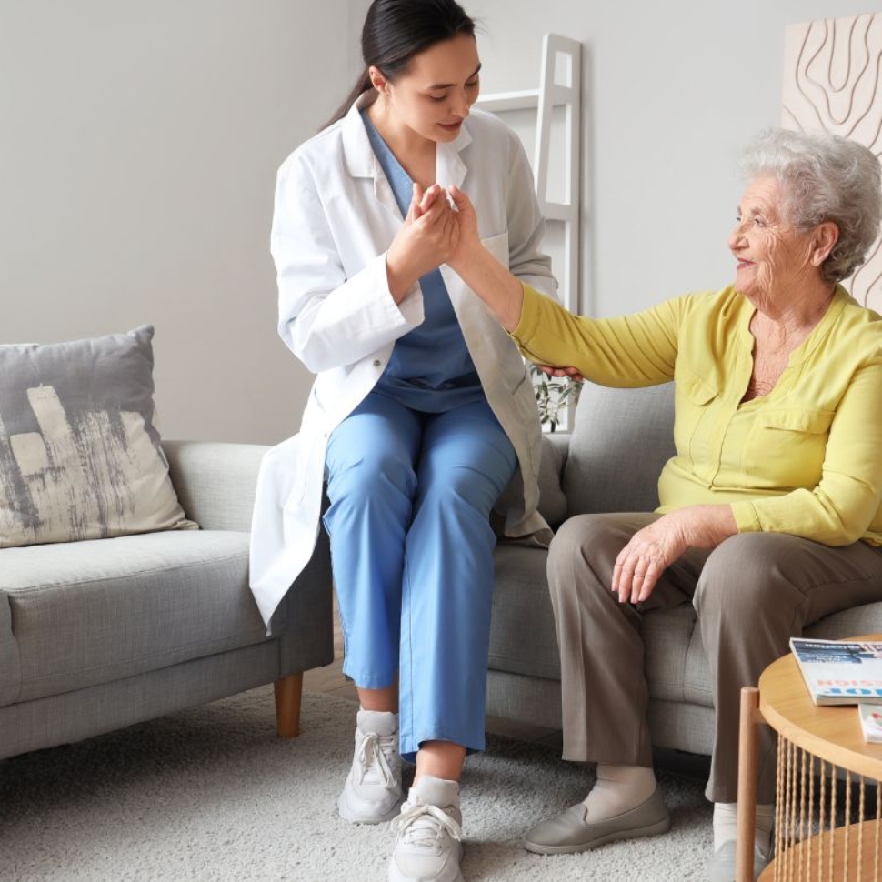 Caregiver providing compassionate in-home support to an elderly woman in a living room setting in Maryland